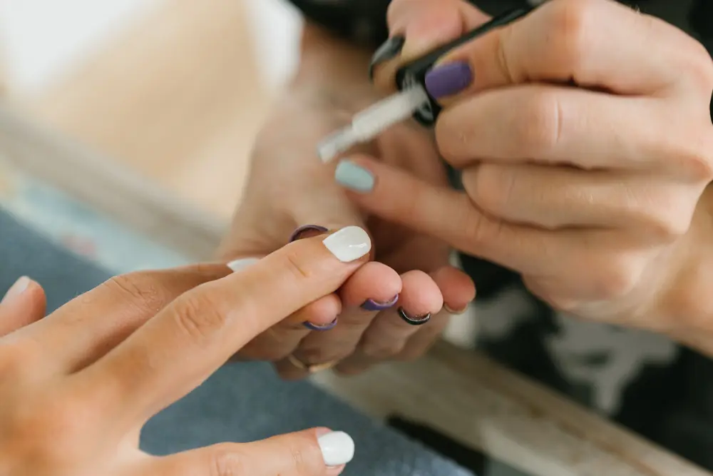 Manicurist painting a client's nails with care